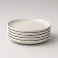 Stack of four Feld Kitchen oatmeal stoneware dinner plates