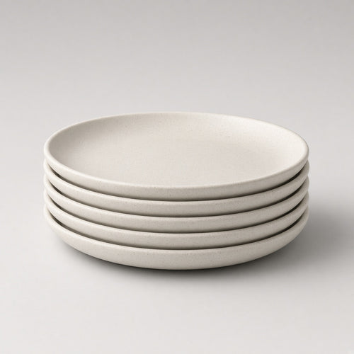 Stack of four Feld Kitchen oatmeal stoneware dinner plates